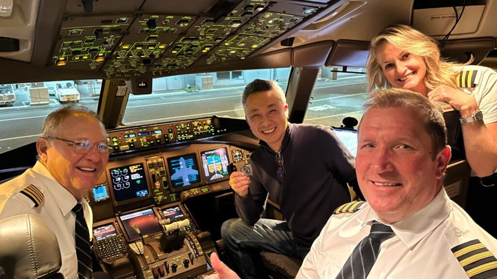 Passenger holding a coin with three pilots in cockpit.