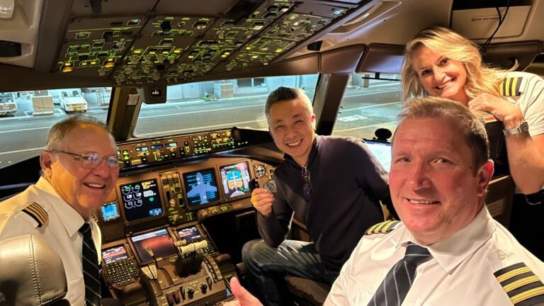 Passenger holding a coin with three pilots in cockpit.