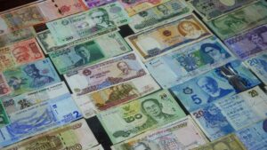 世界各国の紙幣が並べられたフラットレイ構図。多様な通貨が一面に広がる。
