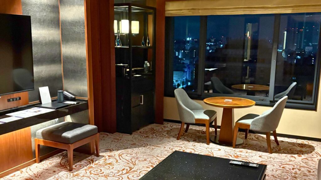 ハイアットリージェンシー横浜の高層階スイートルーム。夜景が見える窓辺にテーブルと椅子、落ち着いた和モダンのインテリア。