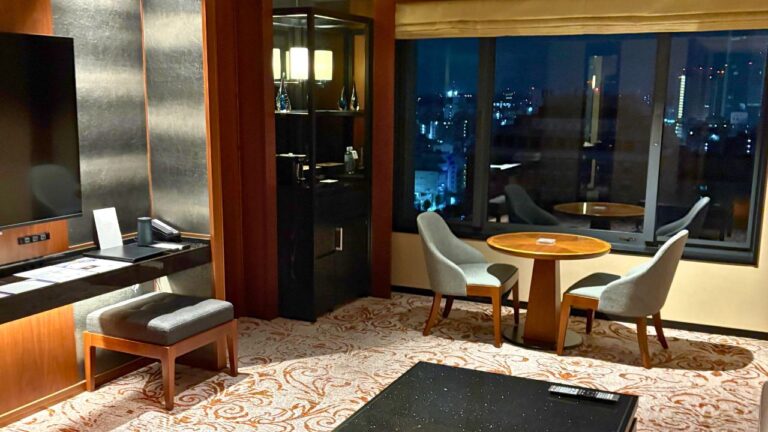 ハイアットリージェンシー横浜の高層階スイートルーム。夜景が見える窓辺にテーブルと椅子、落ち着いた和モダンのインテリア。