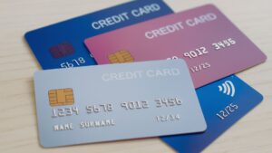 木目調のテーブルの上に、4枚のクレジットカードが色別に重ねて並んでいる様子。