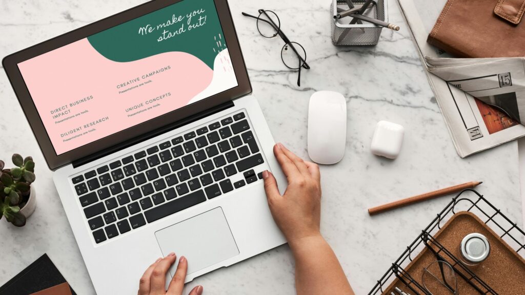 学生のデスクに置かれたノートパソコンとマウス、眼鏡、新聞、文房具など。シンプルで学習や仕事の雰囲気を表すテーブルシーン。