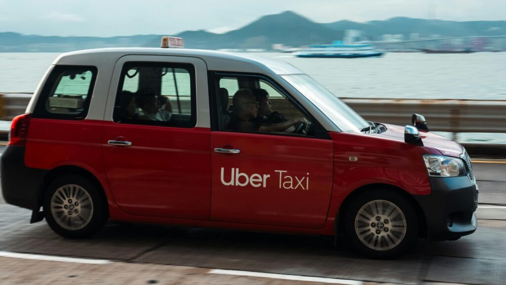 海沿いの道路を走るUber Taxiの車両。Uber CashやUber Oneの特典でよりスマートに利用できる。