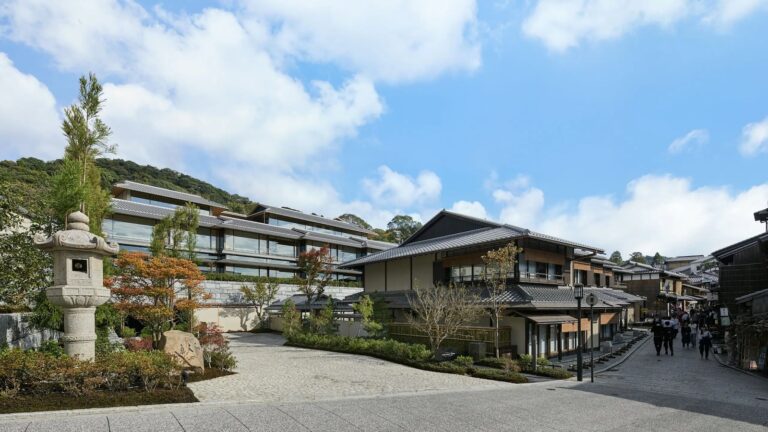 京都・東山の石畳の街並みに面したパーク ハイアット 京都の外観。和風建築の建物と石灯籠、青空が写っている。