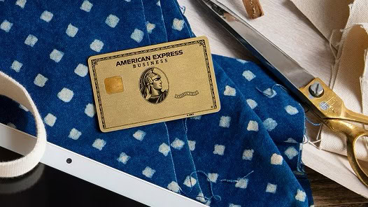 藍染めの布と裁ちばさみ、タブレットが並ぶ作業台に置かれたAmerican Express Business Goldのゴールドカード